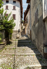 Fototapeta na wymiar Narrow cobblestone streets with stone houses in the small ancient village Naggio in the province of Como, Lombardy, Italy