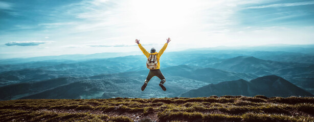 Happy man with open arms jumping on the top of mountain - Hiker with backpack celebrating success...