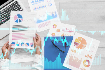 Double exposure of virtual screen with business diagrams and woman working with documents in office