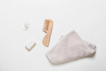 Wooden hair comb, towel, bar soap and pacifier on white background