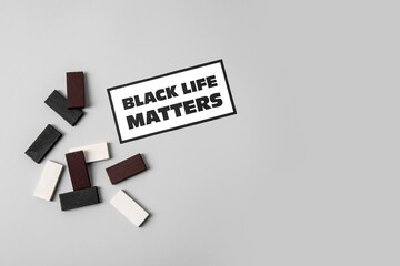 Black, white blocks and paper sheet with text BLACK LIFE MATTERS on grey background
