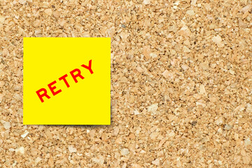 Yellow note paper with word retry on cork board background with copy space