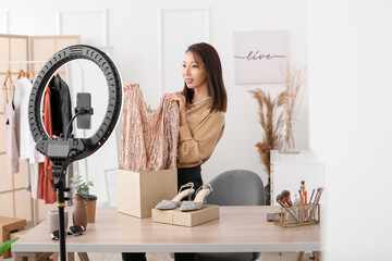 Female Asian beauty blogger with fashionable clothes recording video in studio