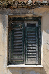 Fototapeta na wymiar Green rotten wooden window at old abandoned traditional house at Corfu Greece