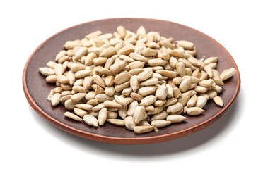 Plate with peeled sunflower seeds on white background