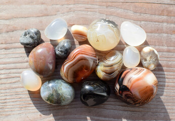 Obraz premium Multicolored gemstones, tumbled minerals. Bostwan agate of various sizes on a wooden background.