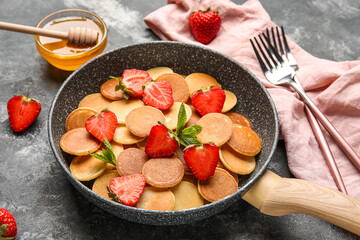 frying pan of mini pancakes with strawberry on grunge background