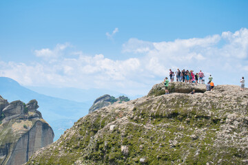 Fototapeta premium People stand on top of rock enjoying the view of the iconic rocks of Meteora in Greece