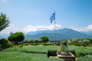 Naklejka premium Greek flag waving in a garden of Orthodox monastery at the top of the iconic rocks of Meteora in Greece