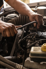 Mãos de um mecânico consertando carro