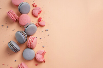 Pink and lilac macarons cookies on a pink background.