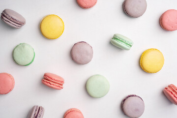 Pink, yellow, green and lilac macarons with cookies on a white background. Background with traditional french dessert.