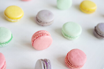 Pink, yellow, green and lilac macarons with cookies on a white background. Background with...
