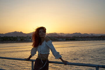 Carefree woman posing in the sunset on the beach. Vacation vitality healthy living concept.Happy travel Woman Enjoying Beautiful sea Sunset on the Beach of Egypt.In the background hilly karst mountain