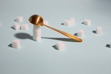 One cube sugar in spoon and many sugar cubes on blue background. Concept flat lay, view from the top.