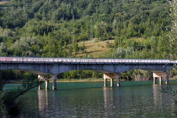 Bridge over the lake of Barrea, Italy. The bridge connects the two shores of Lake Barrea in Italy. The vegetation of the surrounding mountains surrounds the lake.