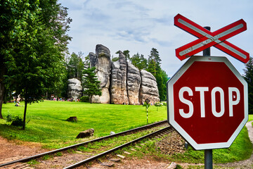 Stop sign in front of narrow-gauge railroad at a group of sandstone boulders on the lawn of the...
