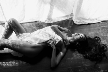 Nude Asian woman lying on wooden floor by window