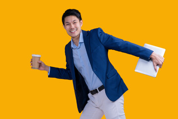 Active Happiness asian cheerful exited young businessman running action while holding tablet and coffee mug in isolated on studio yellow colour background