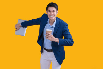 Active Happiness asian cheerful exited young businessman running action while holding tablet and coffee mug in isolated on studio yellow colour background