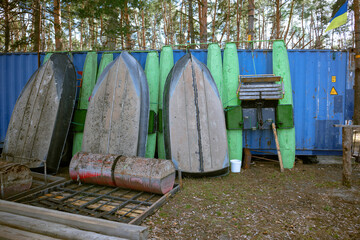 Old metal boats and catamarans stand on land. Vertically standing iron boats and catamarans