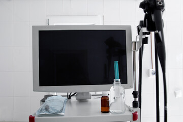 endoscope monitor without image on a white stand with accessories in the endoscopy room against a white wall