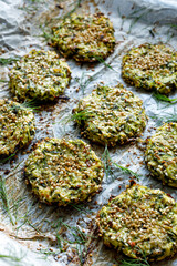 Baked zucchini fritters with fresh dill on baking paper, close-up. Healthy vegetarian food