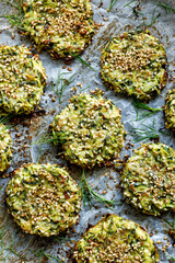 Baked zucchini fritters with fresh dill on baking paper, top view. Healthy and delicious vegan food