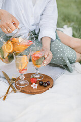 Close up of girl pouring lemonade into glasses at a summer picnic. Beautiful plastic free picnic outdoors.