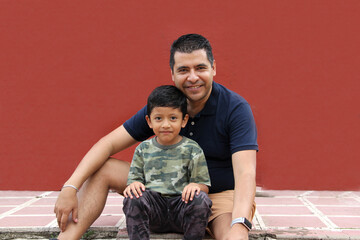 Single dad and dark-haired Latino son play and have fun together spending quality family time on...
