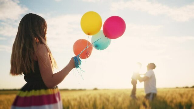 happy family celebrates birthday in the park. girl a holding colorful balloons lifestyle silhouette in the field. dad throws his son into the sky in the park. happy family kid dream concept