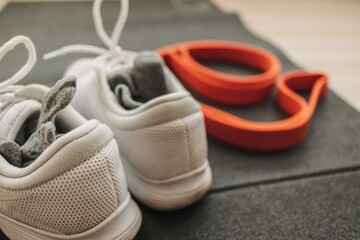 Set of exercise shoes rubber band and workout mat on the home floor.