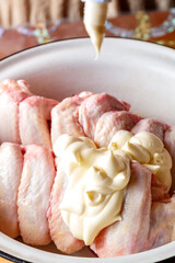 Chicken wings in a dish with mayonnaise and soy sauce. Vertical photo