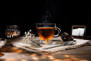 Beautiful glass cup with hot tea on a wooden table with dried flowers, dried lemon and soothing...