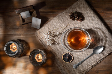 Overhead view of a beautiful glass cup of hot tea on a wooden table with dried flowers, dried lemon...