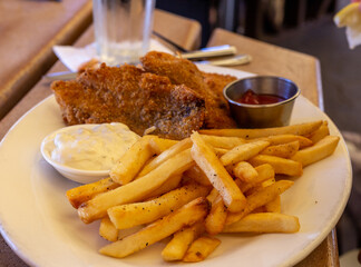 Fish and chips on a plate with two sauces