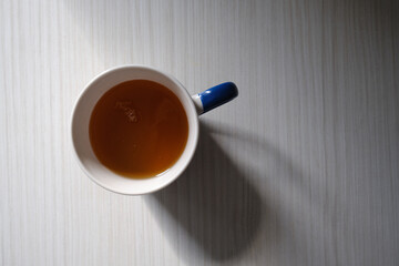 White cup with hot tea on a light wooden background. Place for text
