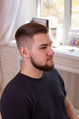Obraz premium Brunette man with stylish haircut on barbershop background 