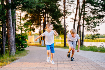 Two boys running and racing each other outdoors in nature. Siblings connection. Friends and...
