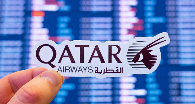 December 11, 2021, Doha, Qatar. The emblem of Qatar Airways against the background of an electronic board with flight schedules at the international airport.