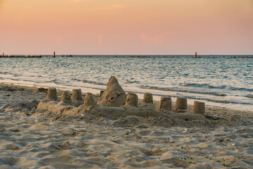 Scena al mare con dei castelli di sabbia costruiti sulla sabbia, al tramonto, in estate, in Italia. Vacanze. Viaggiare. Sera.