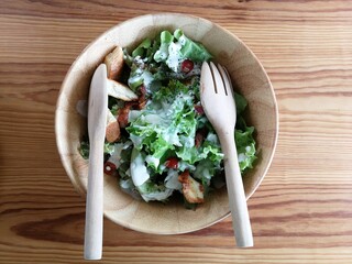 Fresh tomatoes with cucumber, lettuce, red onion and spices in a white bowl. 