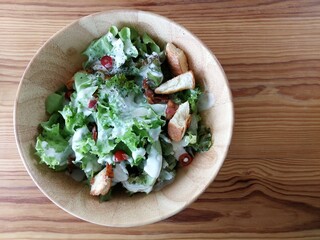 Fresh tomatoes with cucumber, lettuce, red onion and spices in a white bowl. 
