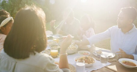 Multi generation asian family eating lunch in a garden at home and bonding. Happy family sitting together with adorable little children. Enjoying and sharing a healthy meal in a backyard gathering