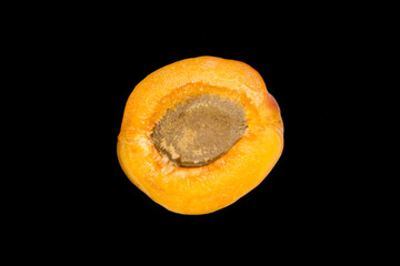 half an apricot with a stone is lying on a black background