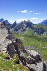 Fototapeta na wymiar Mountain summer landscape. Grassy meadows and rocks under the blue sky. Aerial view on Passo Giau, Italy. Concept of tourism and responsible vacation. High quality image.