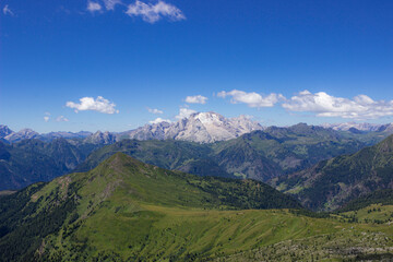 Mountain summer landscape. Grassy meadows and rocks under the blue sky. Marmolada glacier, Italy. Climate change concept. High quality image.