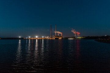 A night view of the lake, in the distance the illuminated chimneys of a coal-fired power plant.