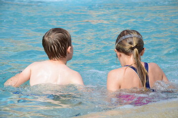Zwei Kinder, ein Junge und ein Mädchen in einem Pool am Meer im Sommer in Italien