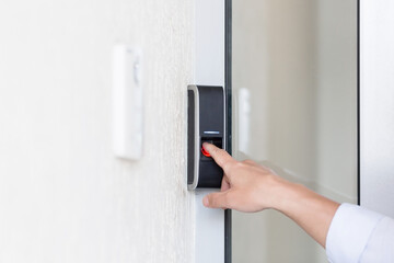 Asian businessman's hand using fingerprint sensor door lock, modern doorbell with video camera.